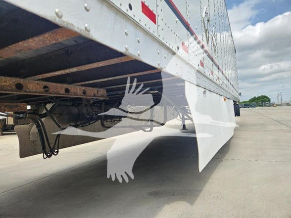 Great Dane trailer undercarriage and side rail showing support framework and fender, with a white decorative graphic of hands reaching from the bottom.