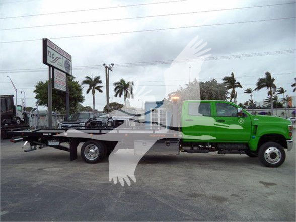 Green 2023 International CV tow truck with flatbed in dealership lot showing VIN and stock number text overlays.