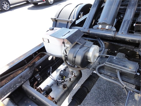 Ram 5500 HD hooklift hydraulic system with white reservoir and motor, mounted on chassis near hydraulic lines and drive components.