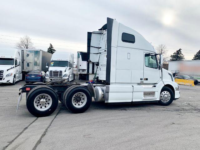 Volvo VNL 670 semi truck in a parking lot, side view showing sleeper cab and rear dual wheels.