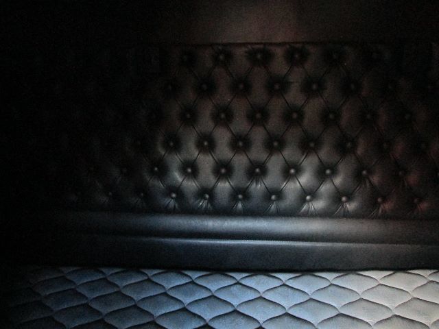 No visible engine or labels; photo shows tufted black leather seat/backrest and lower bench area in a truck cab.