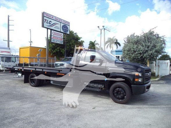 Truck Sales Center lot with a 2023 Chevrolet Silverado 6500HD tow truck flatbed on display.