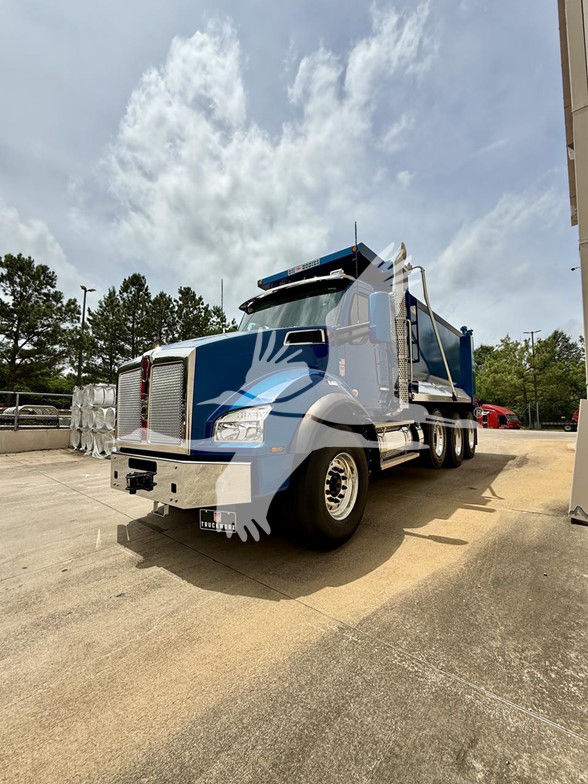 Kenworth T880 dump truck in blue with chrome front grille, large side mirrors, and dual rear axles in a dealership lot.