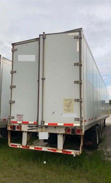 Trailer rear view of a 2012 Wabash Duraplates semi-trailer with double doors, reflective tape, and caution sticker on door.