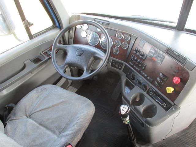 Classic truck cab interior with steering wheel, dashboard gauges, and control panel of a 2007 Freightliner Century sleeper.