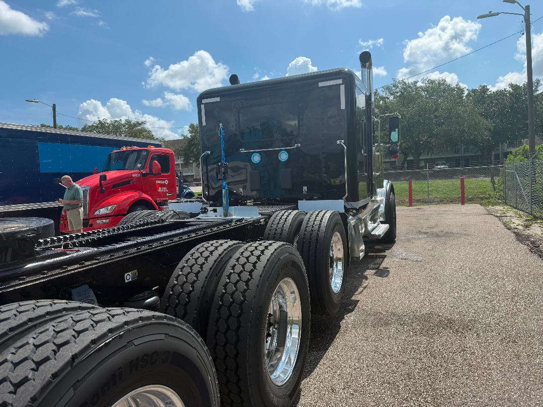 Peterbilt 589 tractor with black cab, dual rear axles, chrome wheels, and fifth wheel in a dealership lot.