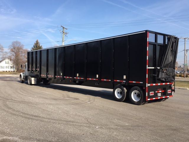 Trailer showing a large black Great Dane single drop trailer attached to a towing truck in a parking lot.