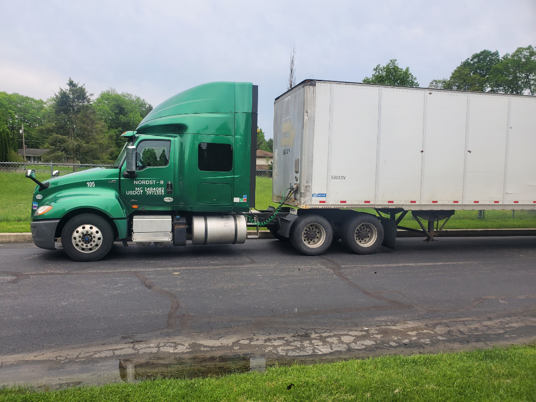 Green 2019 International LT semi-truck tractor with a white box trailer in a parking lot. Visible text includes '105' on front fender and door, pickup details on cab.