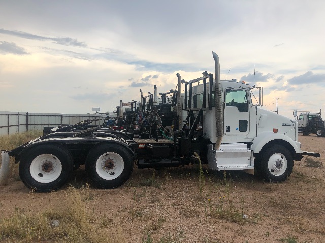 Kenworth T800 truck chassis with long sleeper cab and rollover frame for vacuum equipment, white cab, dual rear axles, flatbed with piping.