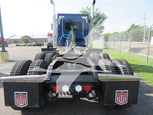Kenworth W900L rear chassis with dual rear axles and mud flaps featuring KW logos; fuel lines and connectors visible; rearview showing fifth wheel area.