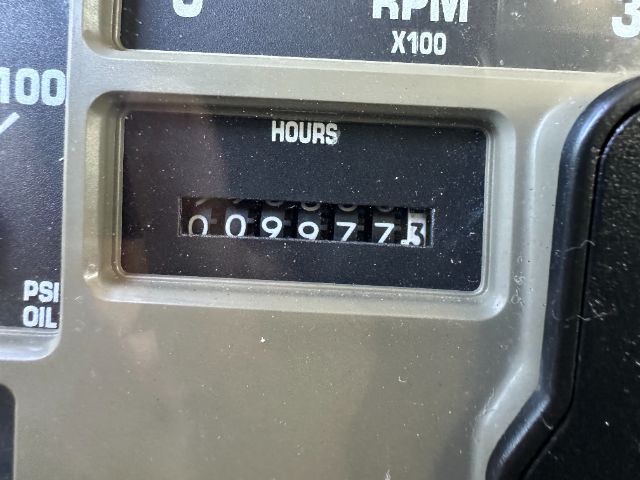 Hour meter showing 0099773 hours on a vehicle dashboard. Partial tachometer scale visible with RPM x100 and other gauges.