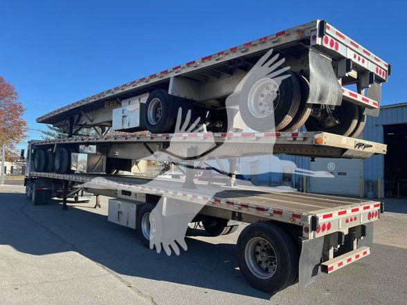 2015 Reitnouer Maxmiser flatbed trailer with two stacked levels showing tires, ramps, and undercarriage.