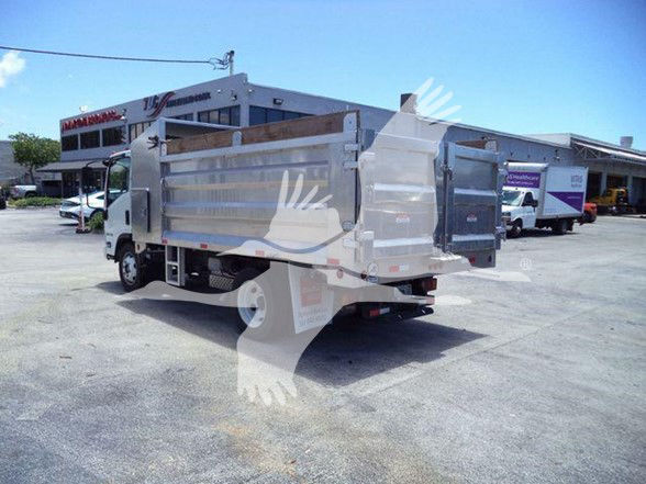Isuzu NQR dump truck in a dealership lot; side of truck shows metal dump bed with side panels. No legible labels or fluid text visible.