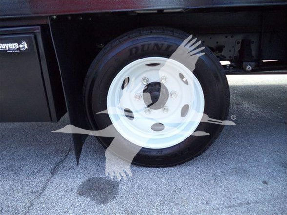 Isuzu NPR HD truck wheel with white steel rim and Dunlop tire visible in a cargo area.