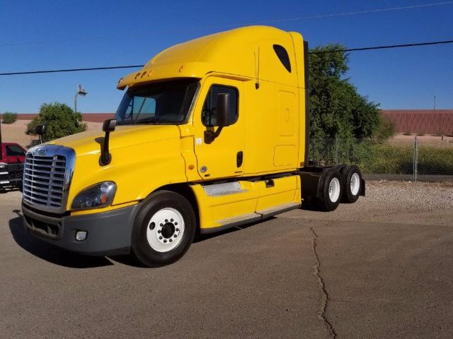 Yellow Freightliner Cascadia conventional sleeper tractor from a side-front angle, showing cab and rear axles.