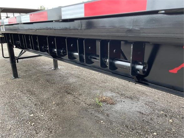 Flatbed trailer side showing extension mechanism and steel frame with black paint.