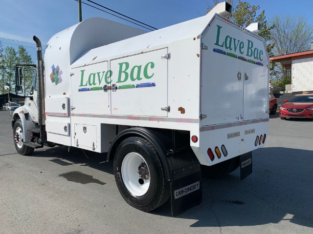 Garbage truck with 'Lave Bac' branding on side and rear doors, rear lights, and white cab. Cargo body shows multiple access panels and compartments.