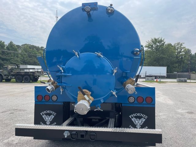 Rear view of a blue septic service truck tank with circular manhole access and multiple hoses fittings. Phoenix branding on mud flaps, rear bumper, tail lights. Tank mounted on chassis.