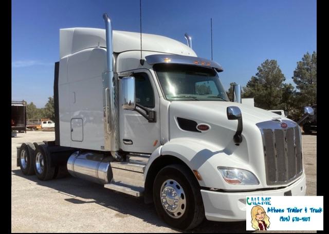 2019 Peterbilt 579 conventional sleeper truck in a light color with a tall aero sleeper, chrome fuel tanks, and dual rear axles; stock number 2875 in the lot.