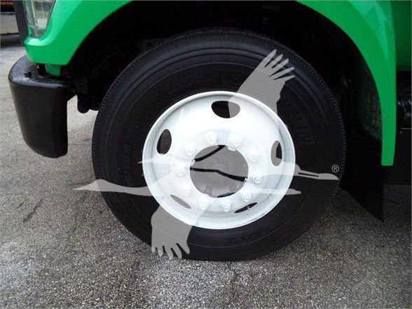 Front wheel and tire of a green Ford F650 SD dump truck showing wheel and tire close-up.