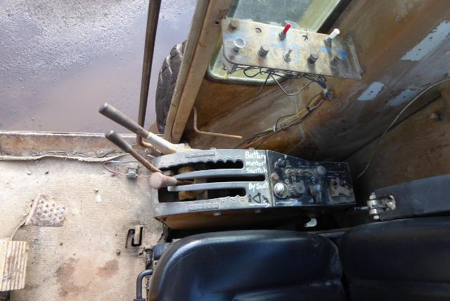 Caterpillar 16G control levers and console inside cab showing pedal area and switch panel.