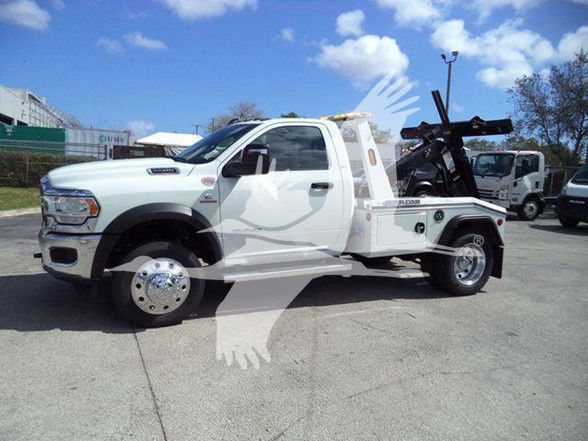 Ram 5500 tow truck in white with heavy-duty flatbed and tow equipment on a sunny day.