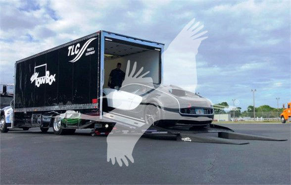 2022 Peterbilt 337 truck being loaded into a large black tow trailer with ramp and forklift visible; truck cab front facing camera.