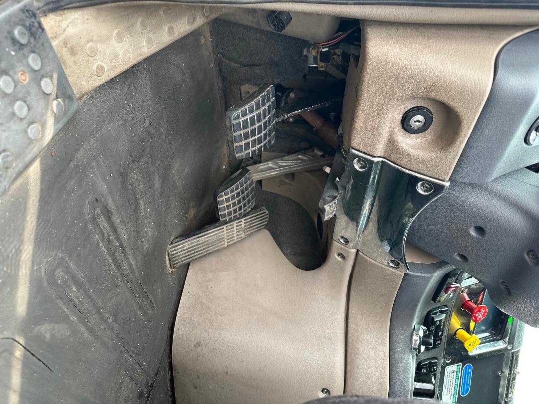 Freightliner Cascadia 2011 dash and pedals area showing accelerator and brake pedals, steering column, and lower dash trim.