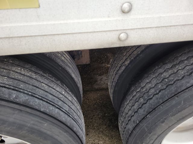 Trailer dual rear axle tires visible under a reefer trailer, showing six-lug wheels and tread patterns.