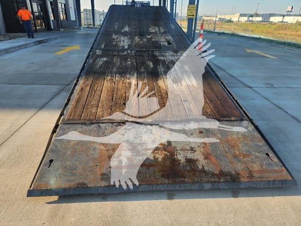 Flatbed trailer ramp with wooden deck showing worn surface and rusted metal frame.