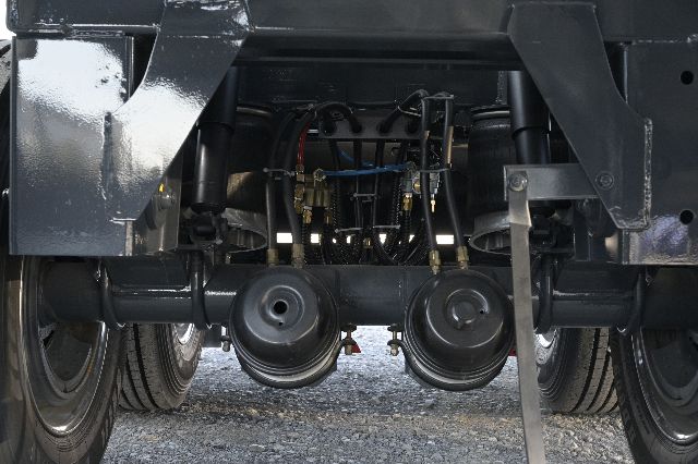 Truxton vacuum trailer undercarriage showing triple axle suspension and fuel lines; mechanical components visible center undercarriage.