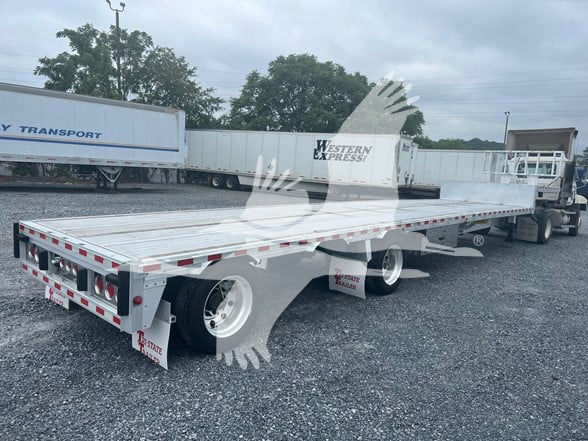 2018 Reitnouer Dropmiser trailer in a parking lot, flatbed with drop deck, rear and side underrun protection, white wheels, truck in background