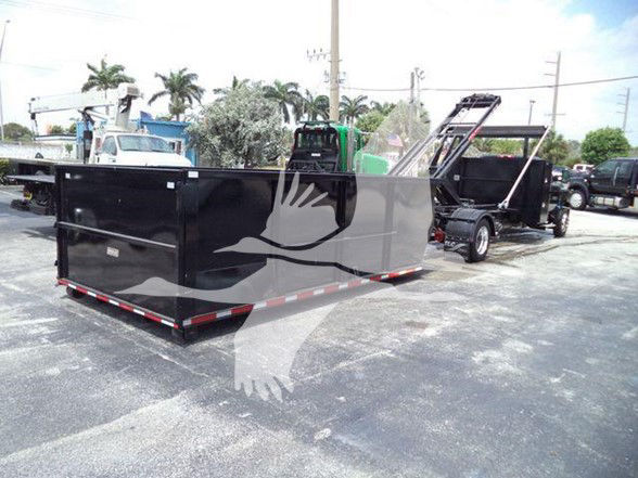 Truck bed dump trailer with hydraulic tailgate in a parking lot.