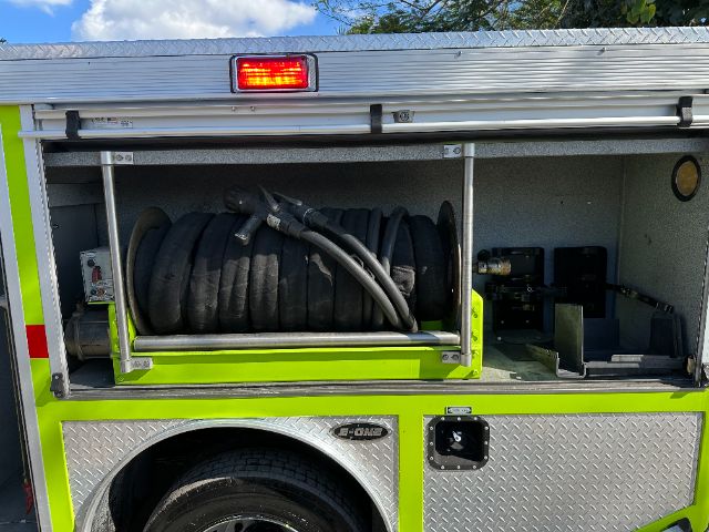 Ford F-550 fire truck rear compartment with extendable hose reel and storage, bright yellow-green body and reflective stripes.