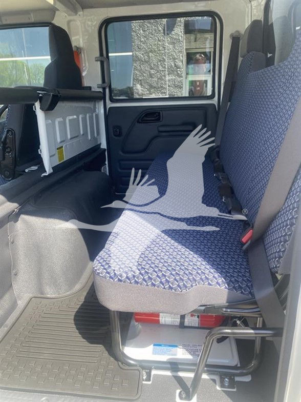 Isuzu NPR HD interior showing rear passenger seat and cargo area with blue patterned upholstery and safety restraints.