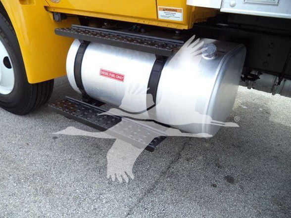 Box truck undercarriage showing large cylindrical fuel tank with silver finish and black straps; part of yellow truck body visible.