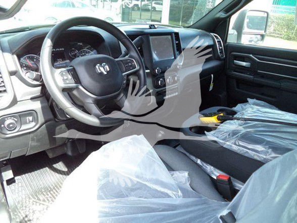 Ram 5500 SLT interior showing steering wheel, center console with touchscreen, and driver seat wrapped in plastic.