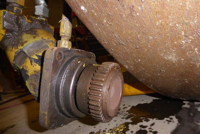 Bomag BW212D-2 component showing a large gear coupling and hydraulic line near a rusted drum.