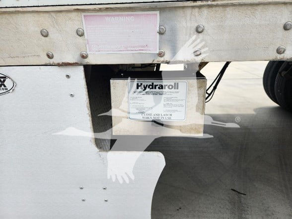 Hydraroll label on underside of trailer frame with warning sticker above it.