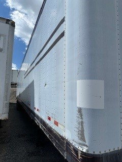 Trailer side of a Great Dane dry van with light blue exterior, showing some wear near lower edge and white rectangular reflective patches.