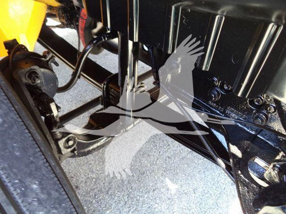 Industrial truck undercarriage showing metal frame, bolts, hydraulic lines and a black painted surface with ribbed components.