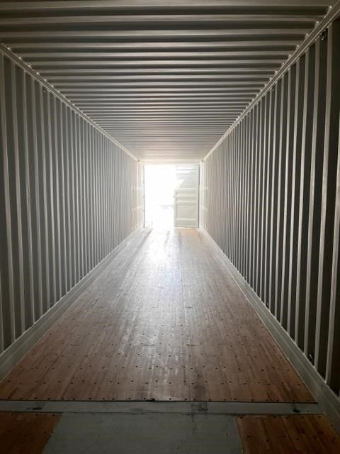Container interior showing corrugated steel walls and wood-like deck floor with open end.