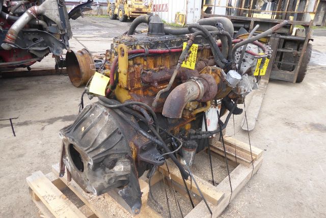 Industrial engine on pallet with hoses and yellow tags; rusted metal surfaces and a large turbo inlet on the left.