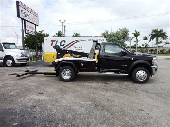 2024 Ram 4500 SLT tow truck with a black cab and a flatbed/wrecker setup in a dealership lot.
