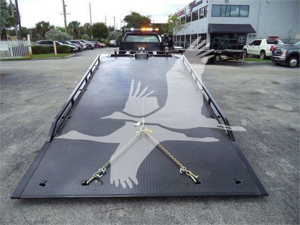 Tow truck flatbed with alloy diamond plate surface and front towing hooks, Chevrolet Silverado 6500HD listing in background.