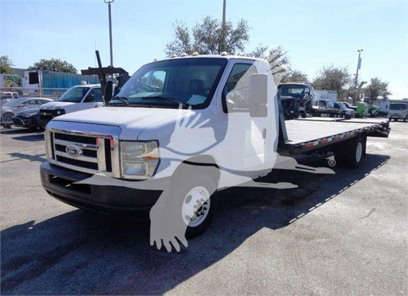 Ford E-450 flatbed truck, front-left angle with VIN and stock number in listing; cab shows Ford grille and flatbed; no engine bay text visible.