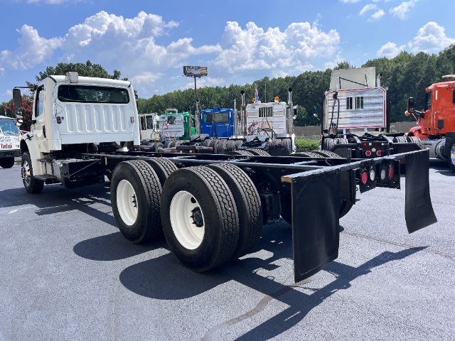 Truck chassis with rear dual-axle configuration, white cab, black frame, and mud flaps visible; no legible labels or plates in view.