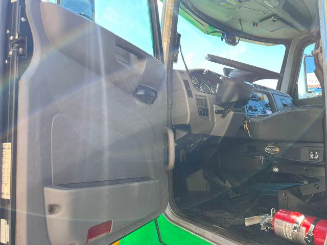 Truck interior: open driver door of a 2016 Peterbilt 348 rollback truck showing the dash, steering wheel, pedals, and seat. Visible text includes 'GEOTSA' badge on the glove area and various gauges.