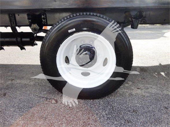 Wheel and tire on Freightliner BUSINESS CLASS M2 106 truck, white steel rim, undercarriage visible.
