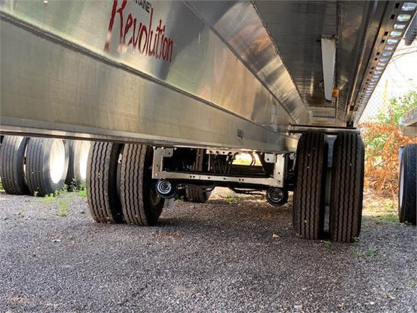 Flatbed trailer undercarriage with multiple axles and tires, aluminum body visible, Kanevolution-style branding on side.
